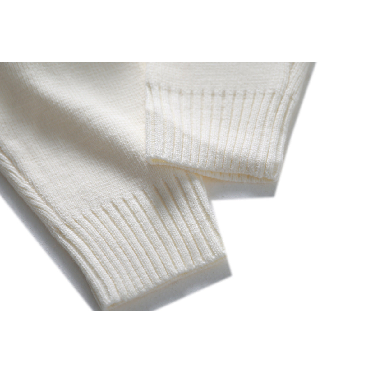 Close-up of an ivory knit sweater’s ribbed cuffs and sleeve ends.