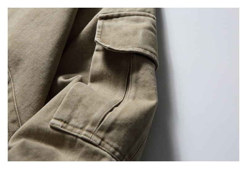 Close-up of a taupe jacket sleeve with a flap pocket and visible stitching.