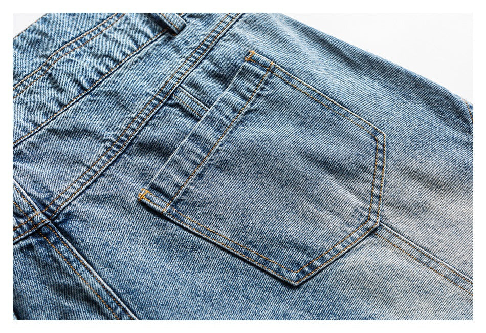 Close-up of a blue jeans back pocket with orange stitching and faded denim.