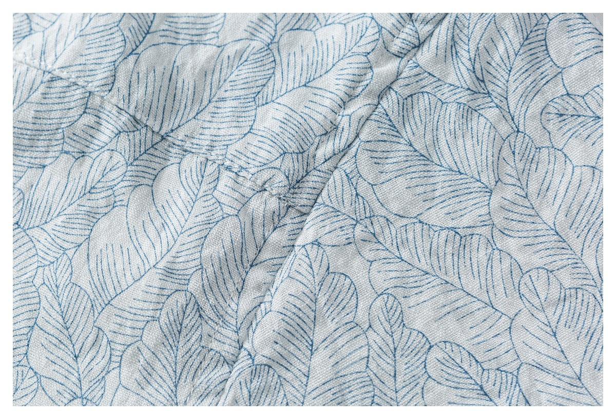 Close-up of blue leaf-patterned fabric with a diagonal fold and visible woven texture.