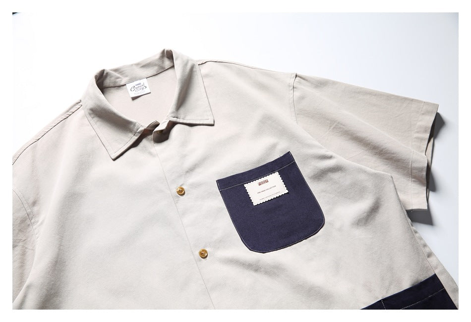 Close-up of the shirt's light gray collar and upper front, with tan buttons and a navy chest pocket.