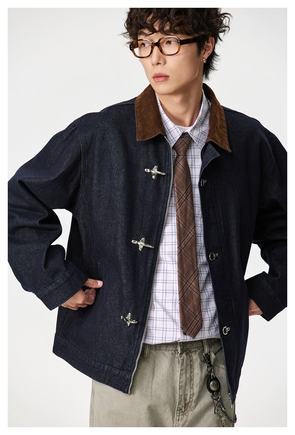 Model wearing a dark indigo jacket with a brown collar and metal clasps, shown from the front.