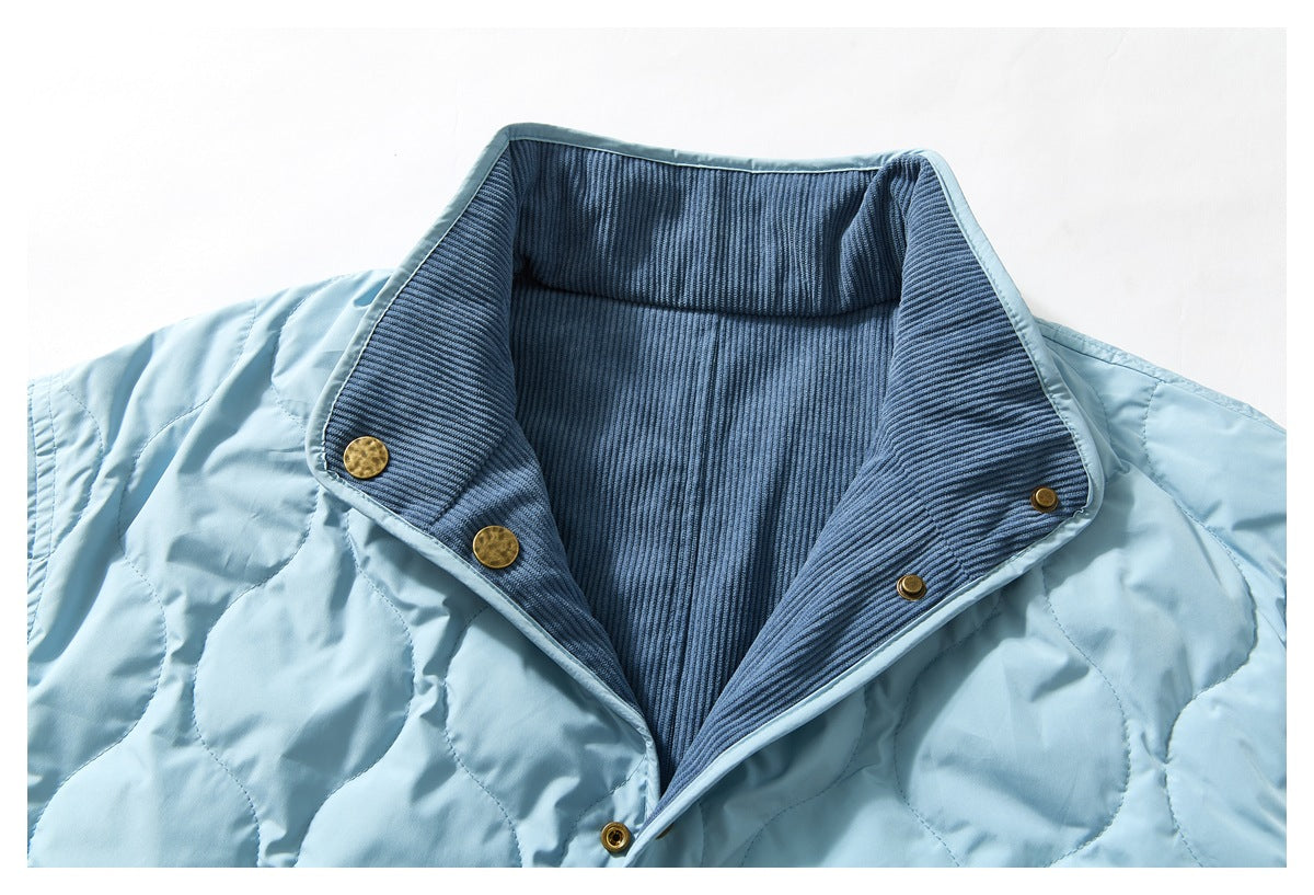 Close-up of a pale blue quilted jacket with a dark blue ribbed inner collar and brass-tone snaps.