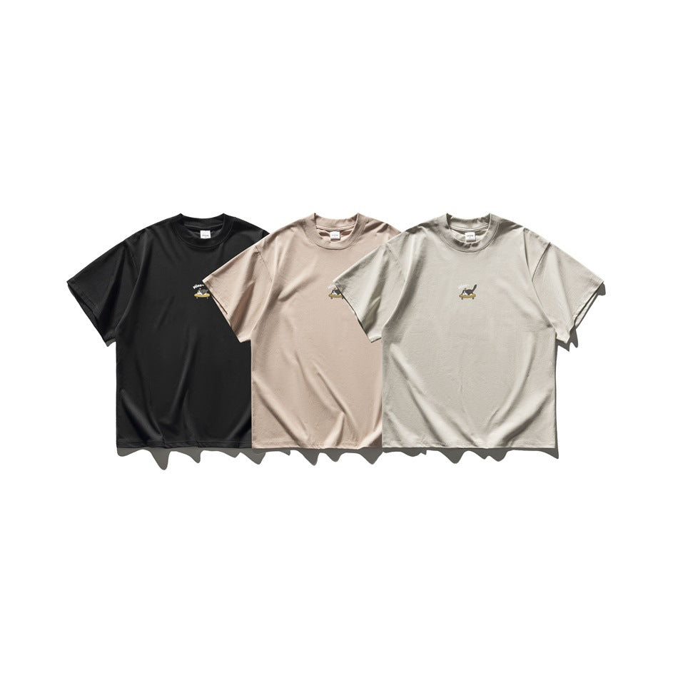 Fronts of three short-sleeve crew-neck T-shirts in black, blush, and light beige, each with a small cat graphic on the chest.