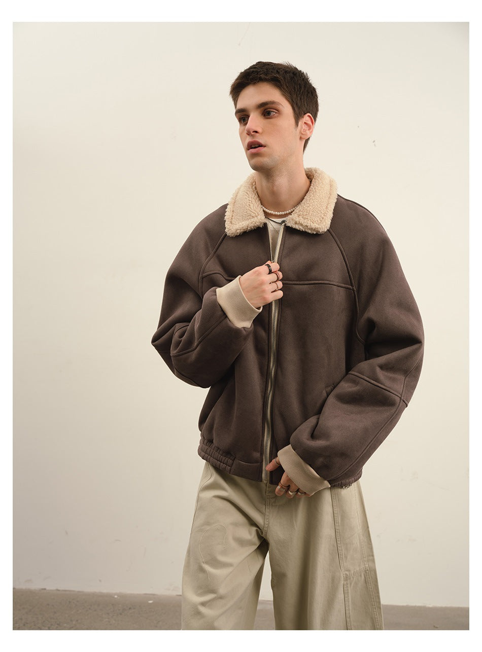 Model wearing a brown zip-front jacket with a fleece-textured collar and light khaki pants, hand at the zipper