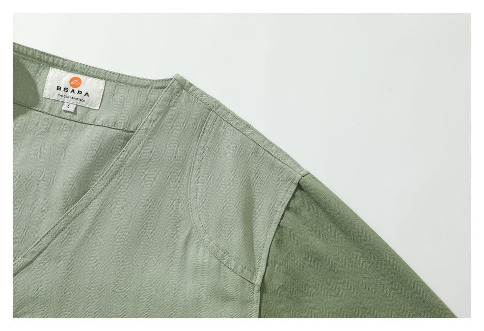 Close-up of the sage-green garment’s neckline, shoulder seam, and sewn-in BSAPA label.