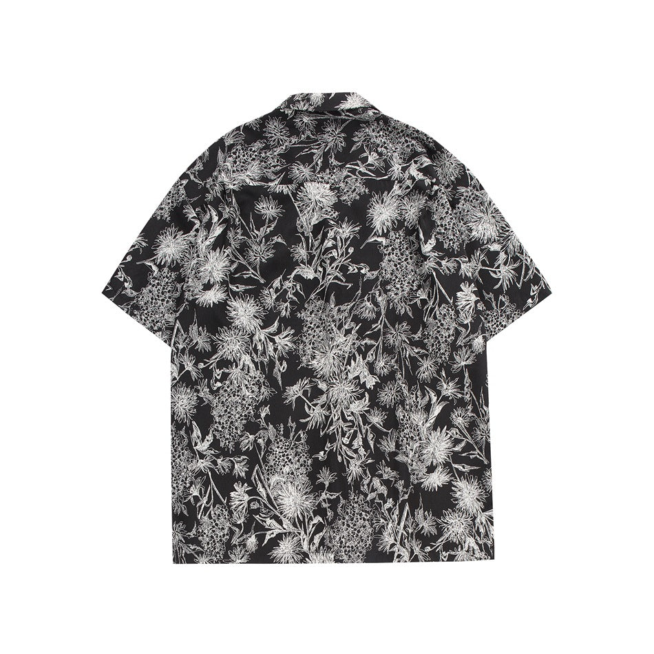 Flat back view of a black short-sleeve shirt with an all-over white botanical print.
