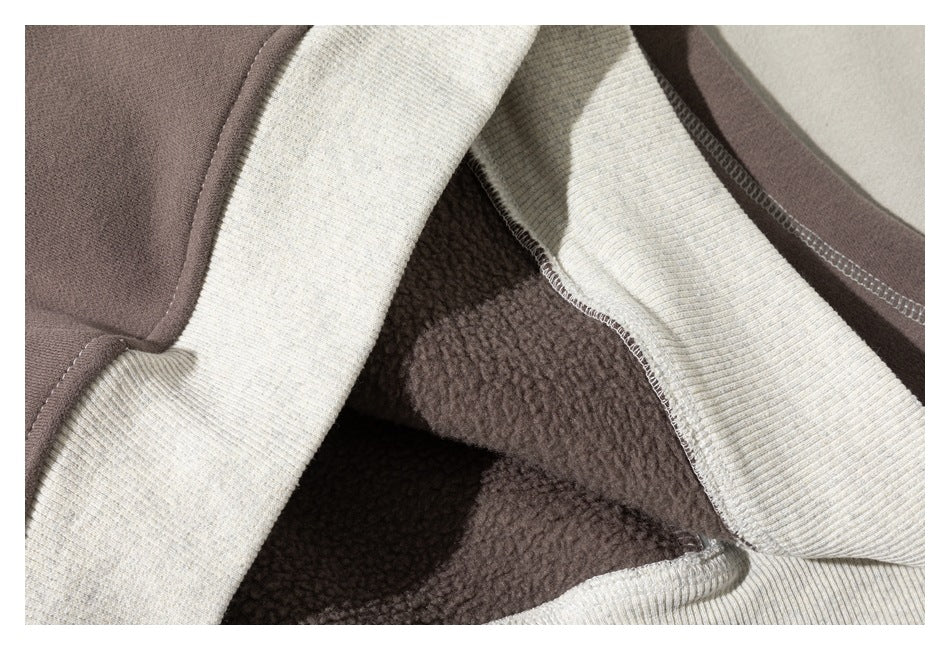 Close-up of a color-block sweatshirt showing dark brown fuzzy inner fabric, cream ribbed fabric, and stitched seams.