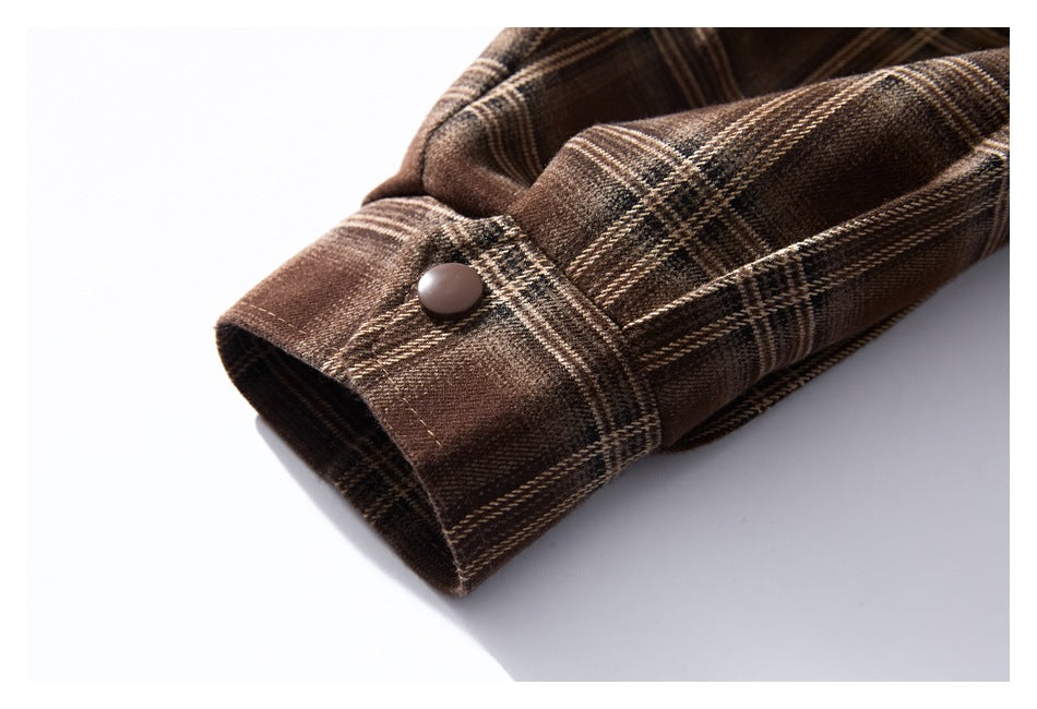 Close-up of a brown plaid sleeve cuff with a dark snap button.