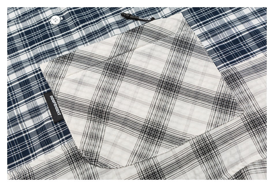 Close-up of a navy plaid shirt pocket in contrasting black-and-white plaid, with a white button nearby.