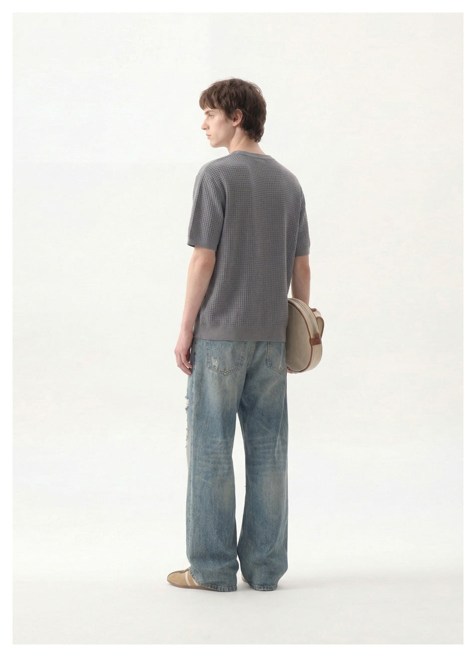 Rear view of a model wearing a gray textured short-sleeve top and loose blue jeans.
