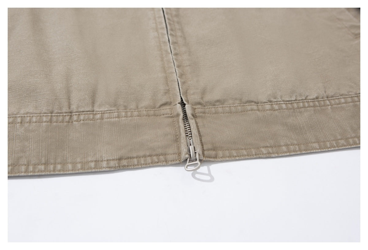 Close-up of the taupe jacket's hem and center-front zipper with a loop-shaped pull.