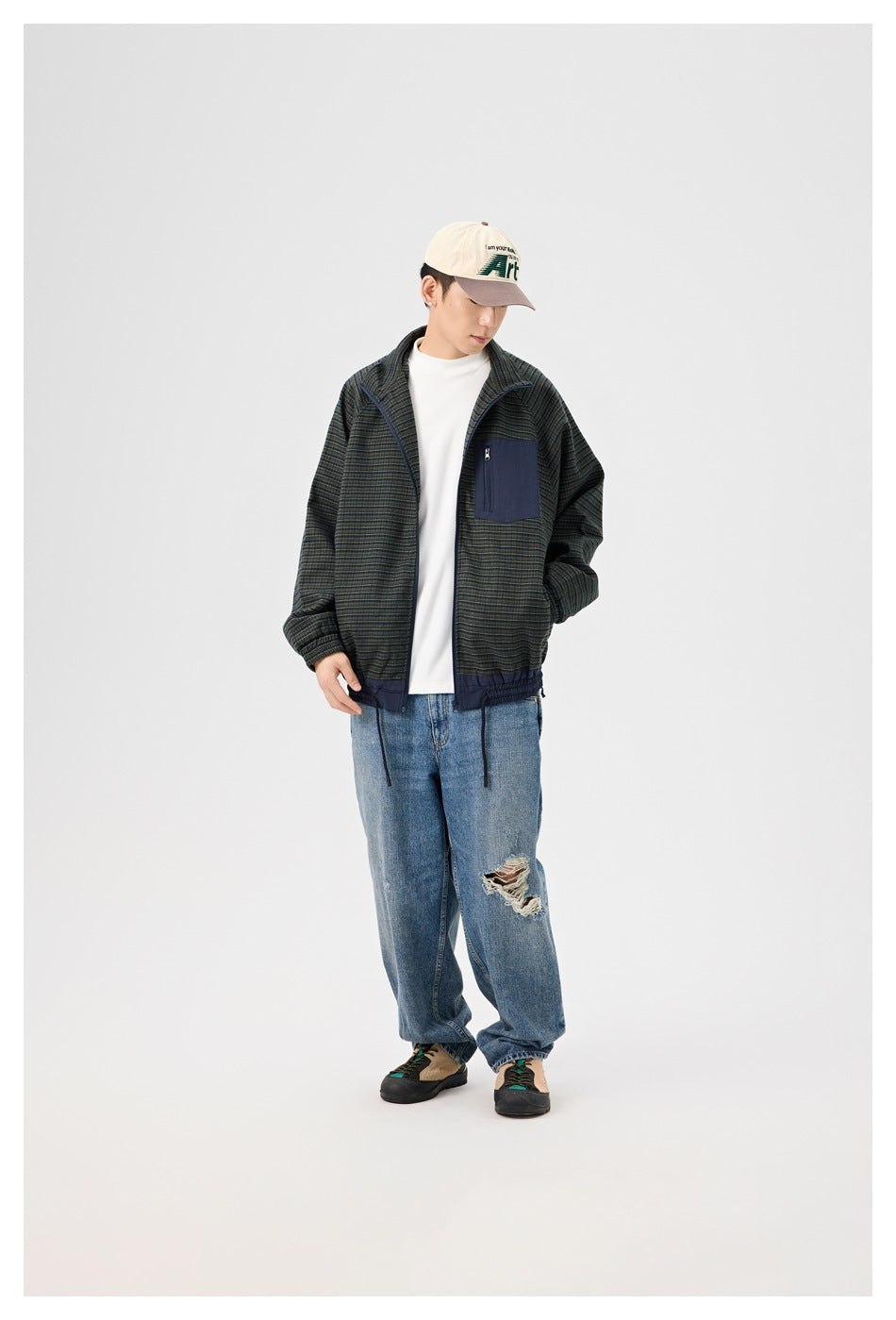Full-length view of a man wearing a dark striped jacket with a navy chest pocket and loose blue jeans.