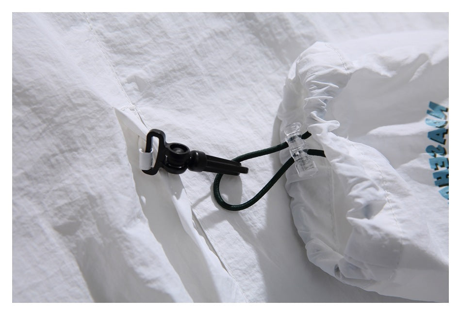 Close-up of the white jacket's hem drawcord, black toggle and green cord.
