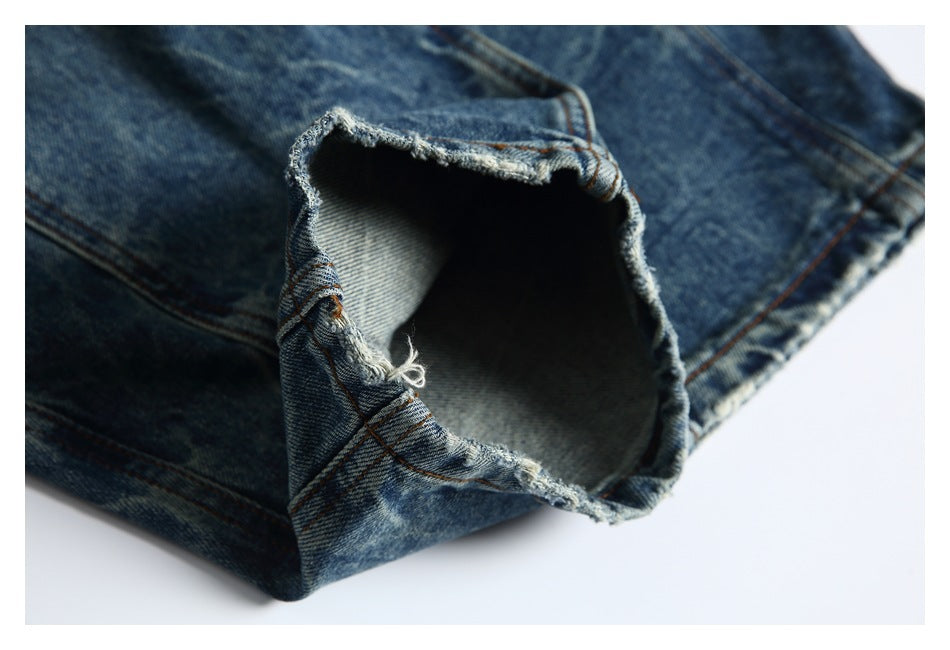 Close-up of a frayed opening and distressed hem on blue denim jeans.