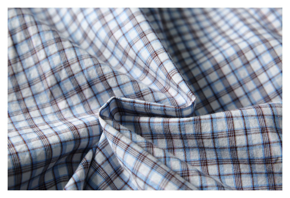 Close-up of draped white shirt fabric with a blue and brown plaid pattern.