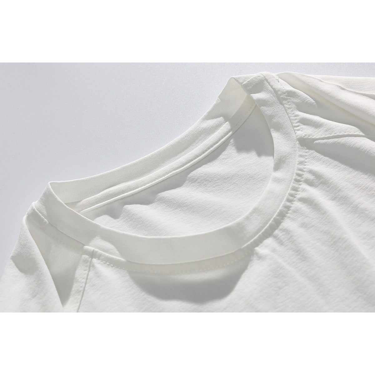 Close-up of the crew neckline and shoulder seams on a plain white T-shirt.