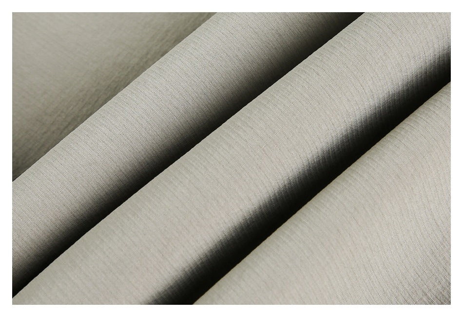 Close-up of light gray-beige fabric arranged in folds, showing a subtle fine linear texture.