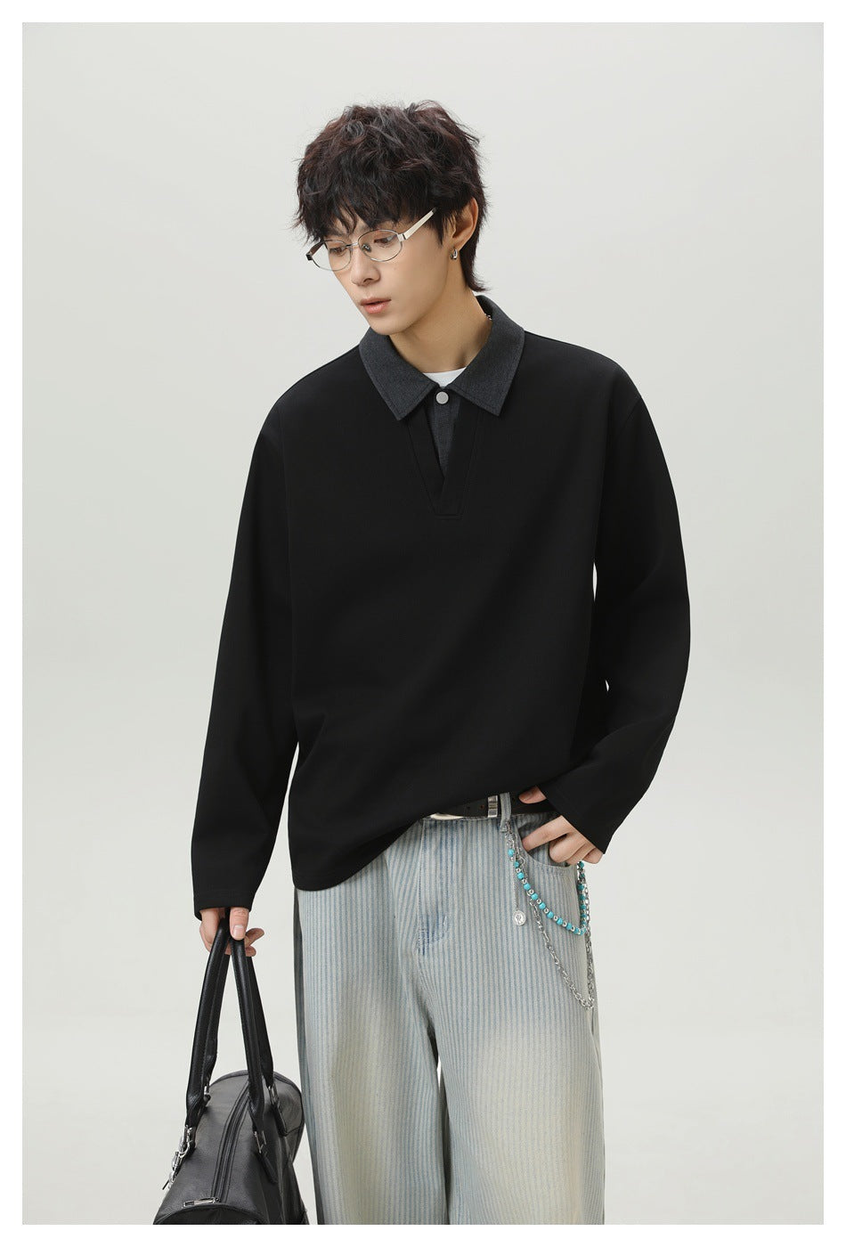 Model wearing a black long-sleeve top with a charcoal collar and buttoned V-placket, paired with pale striped pants.