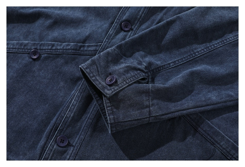 Close-up of a dark indigo garment with an overlapping sleeve, buttoned cuff and several dark buttons.