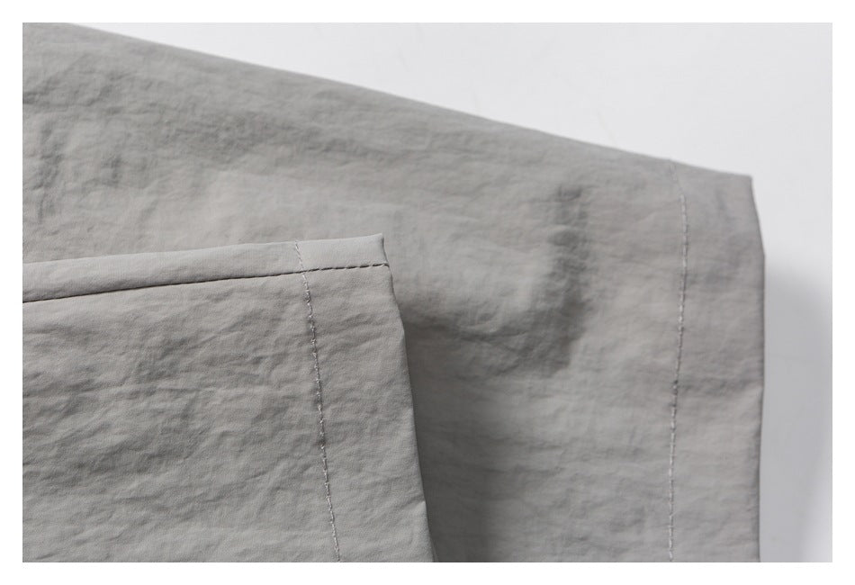 Close-up of gray garment fabric with a folded edge and parallel stitching.