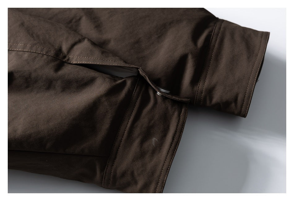 Close-up of a dark brown jacket sleeve and adjustable side tab with a metal fastener.