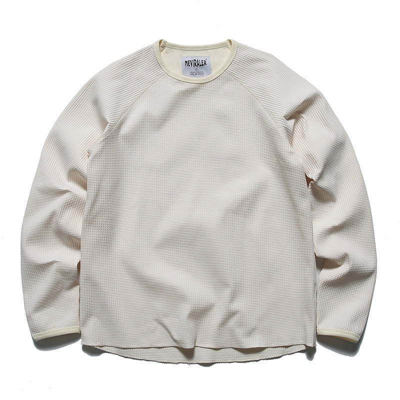 Front view of an off-white long-sleeve waffle-knit crewneck shirt with raglan seams.