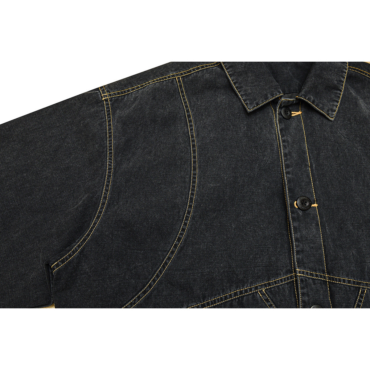 Close-up of a charcoal denim jacket's curved seam, shoulder stitching and button placket.