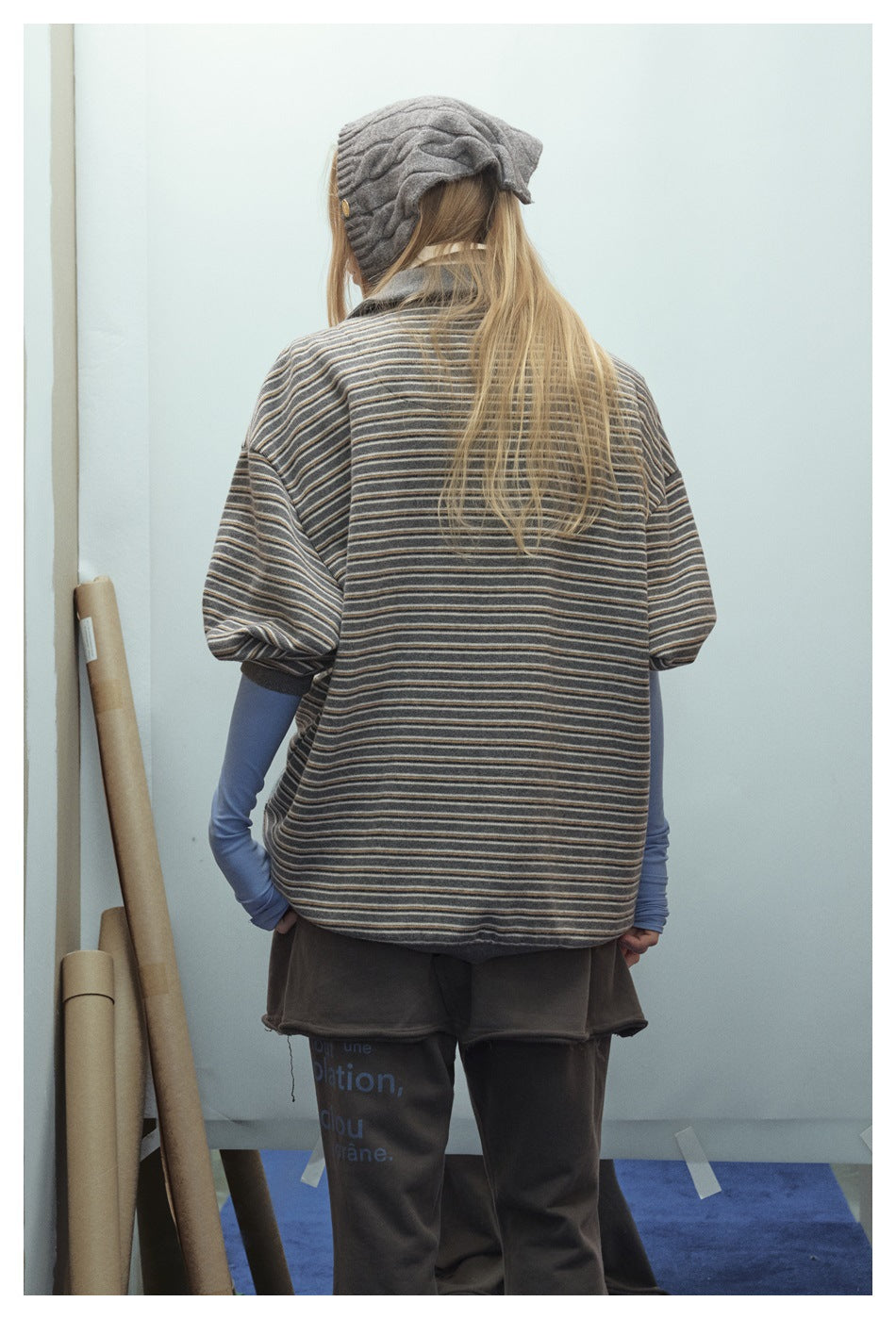 Back view of a model wearing an oversized gray striped pullover with short sleeves and contrast trim.