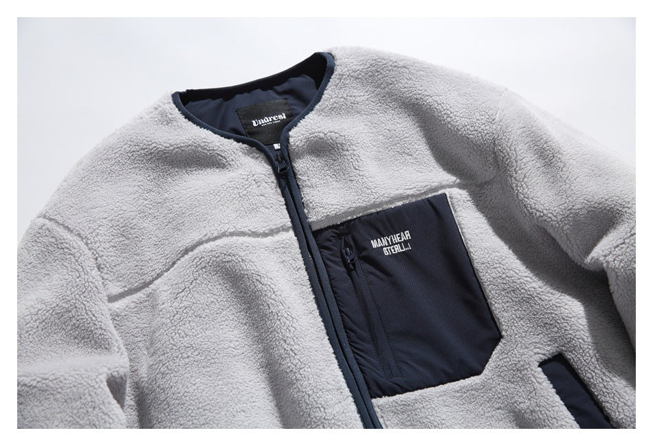 Close view of a light gray sherpa fleece jacket with a navy full-length zipper and contrasting chest pocket.