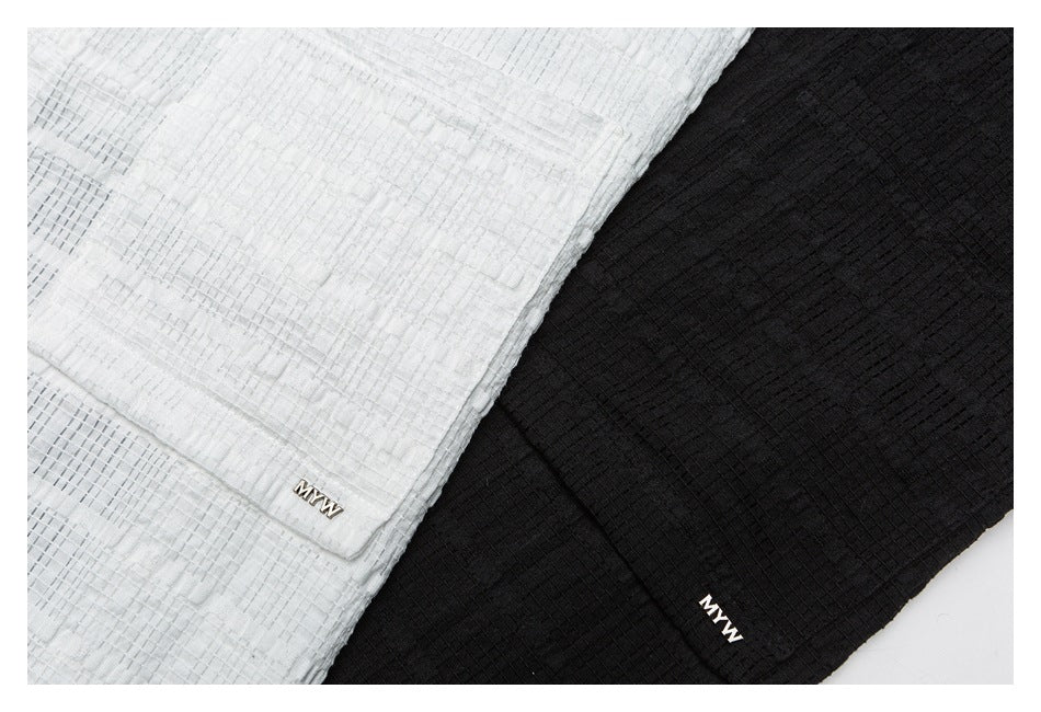 Close-up of the textured white and black shirts, showing their fabric pattern and small garment logos.
