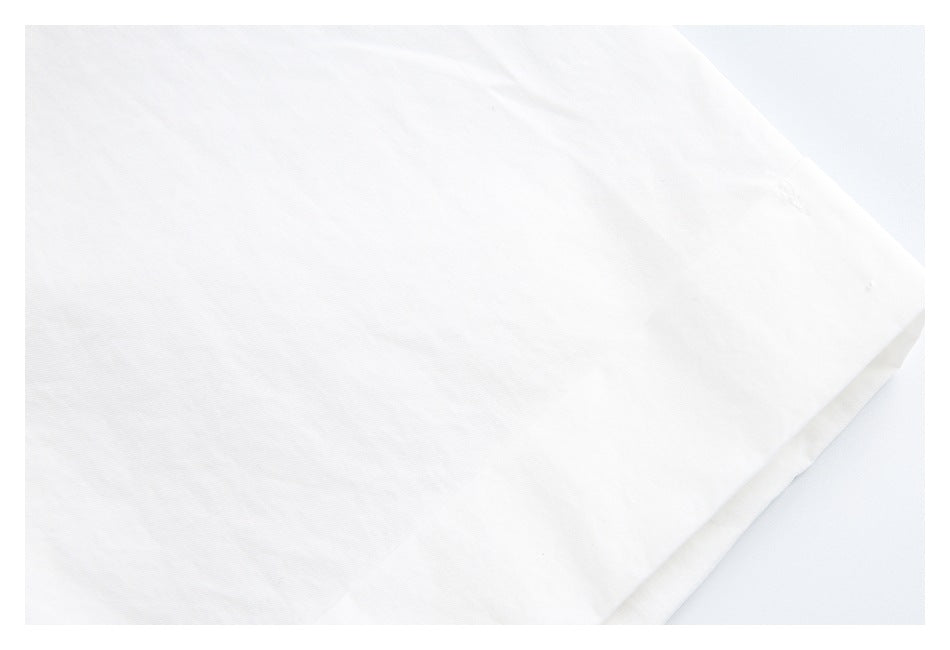 Close-up of white garment fabric and a folded, stitched edge.