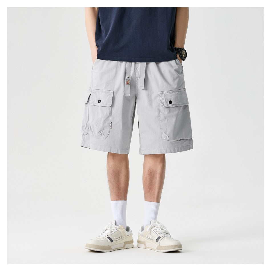 Front view of a model wearing light gray cargo shorts with a drawstring waist and flap pockets.
