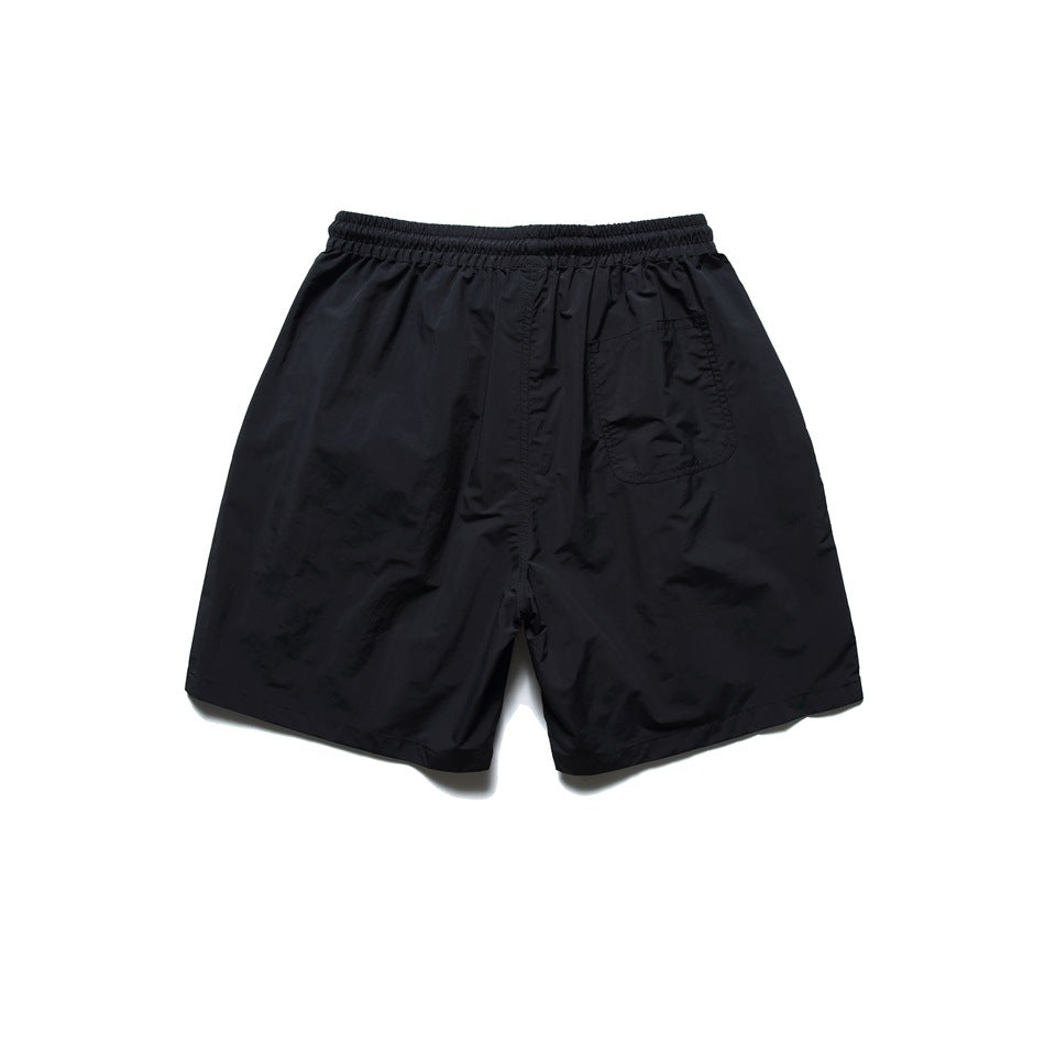 Back view of black shorts with an elastic waistband and a single patch pocket.