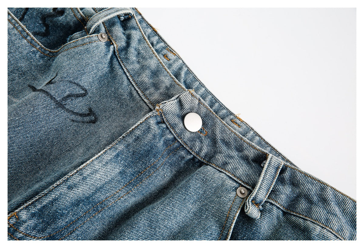 Close-up of the jeans' waistband, metal button, belt loops, and front fly area.