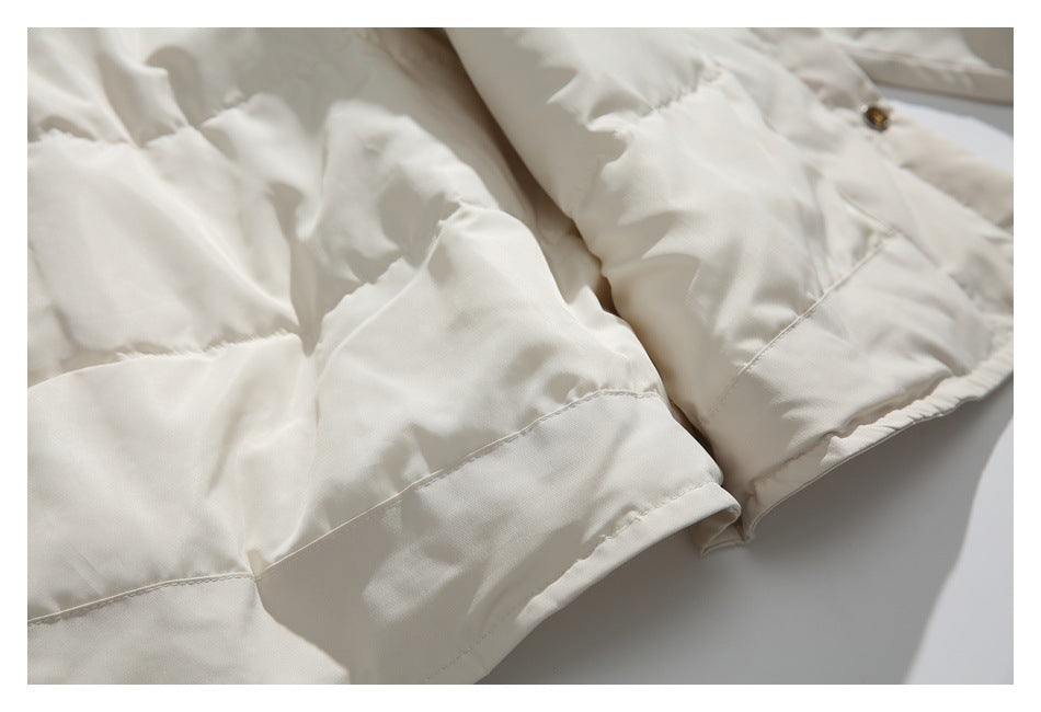 Close-up of an ivory padded garment's hem and sleeve, with stitched seams and a snap button.