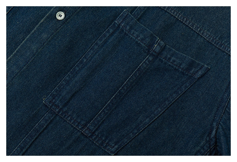 Close-up of a rectangular chest pocket and stitching on a dark indigo denim shirt.