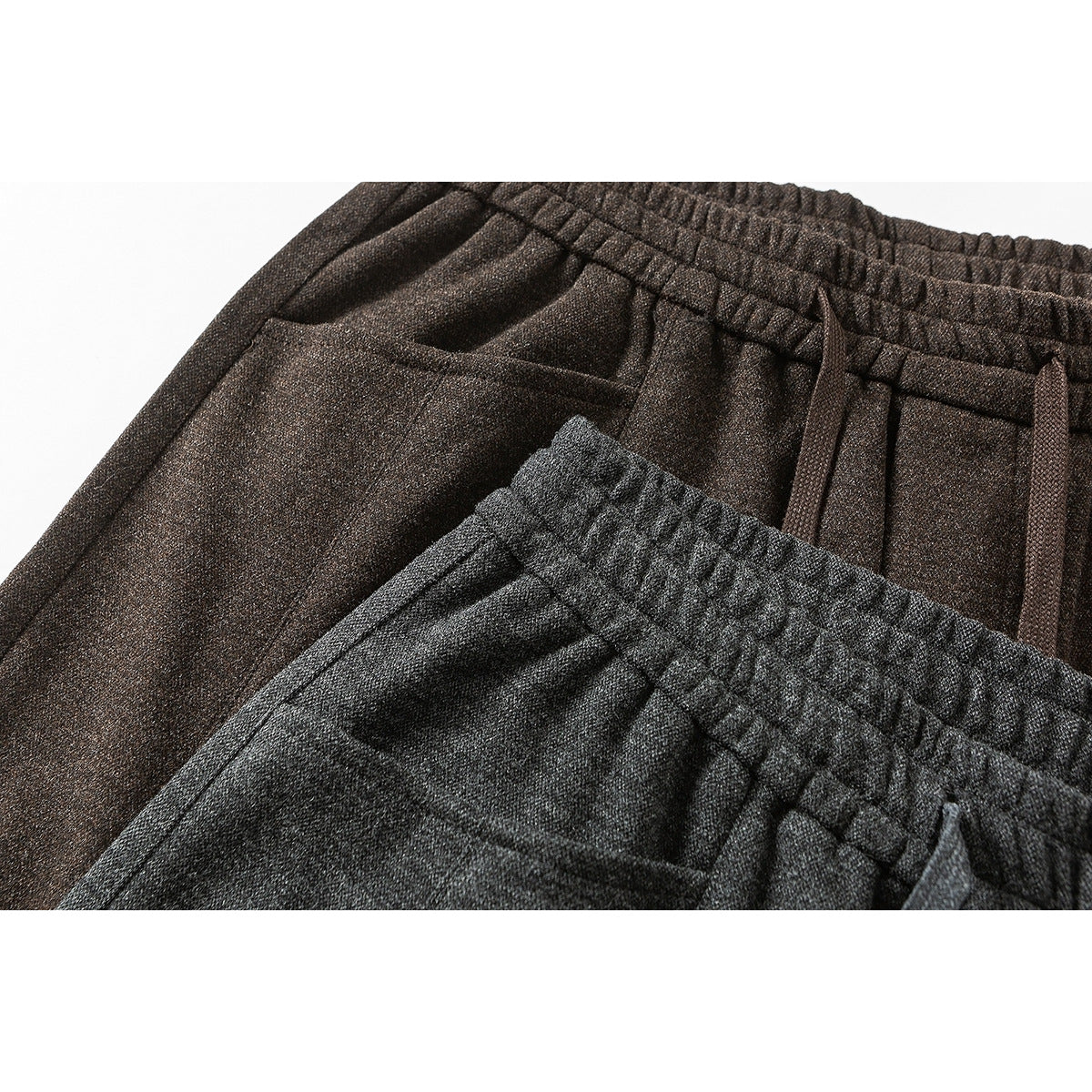 Close-up of charcoal and dark brown wide-leg pants showing elastic waistbands, drawstrings, and front pockets.
