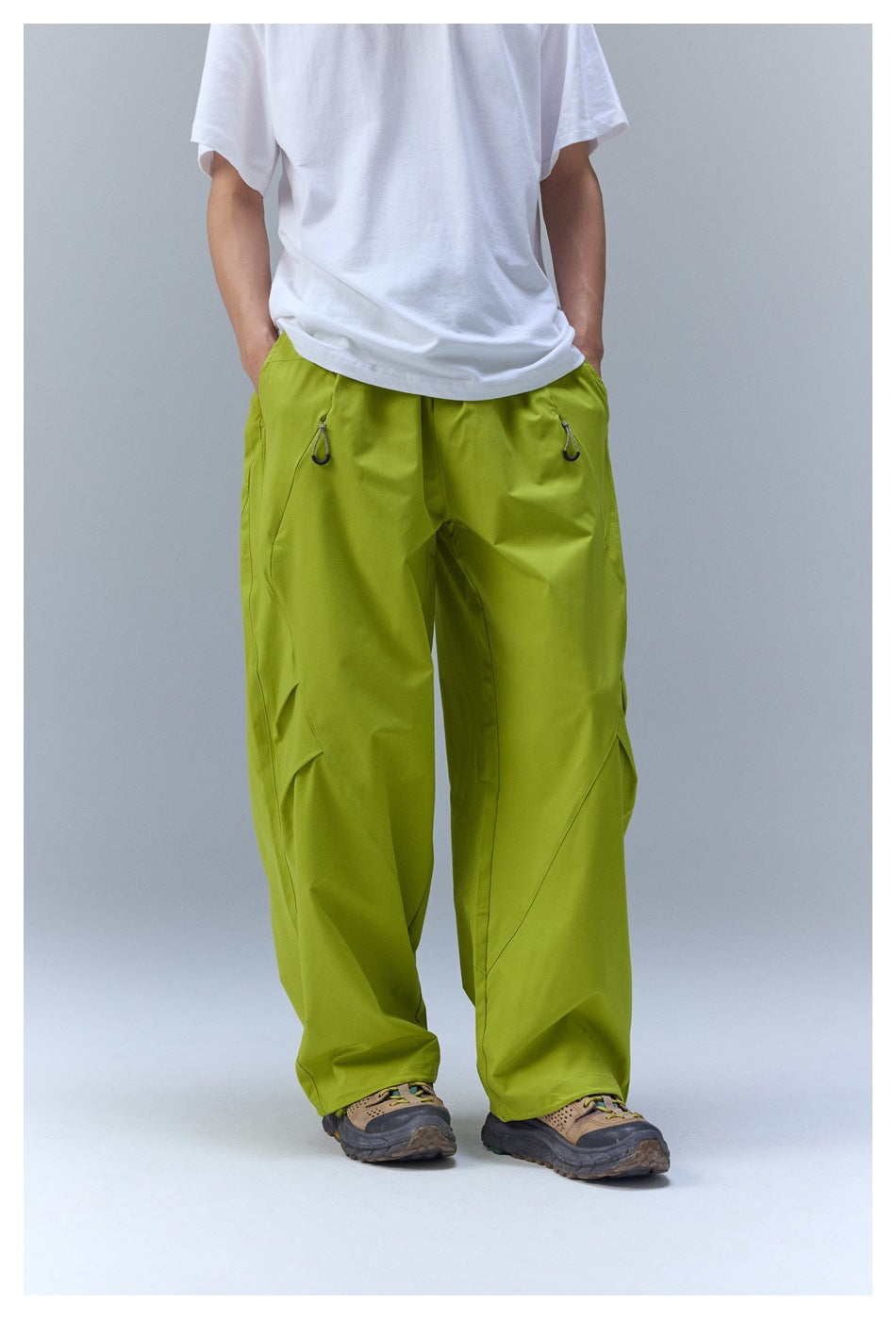 Person wearing yellow-green wide-leg pants with a white T-shirt and hiking-style shoes, front view