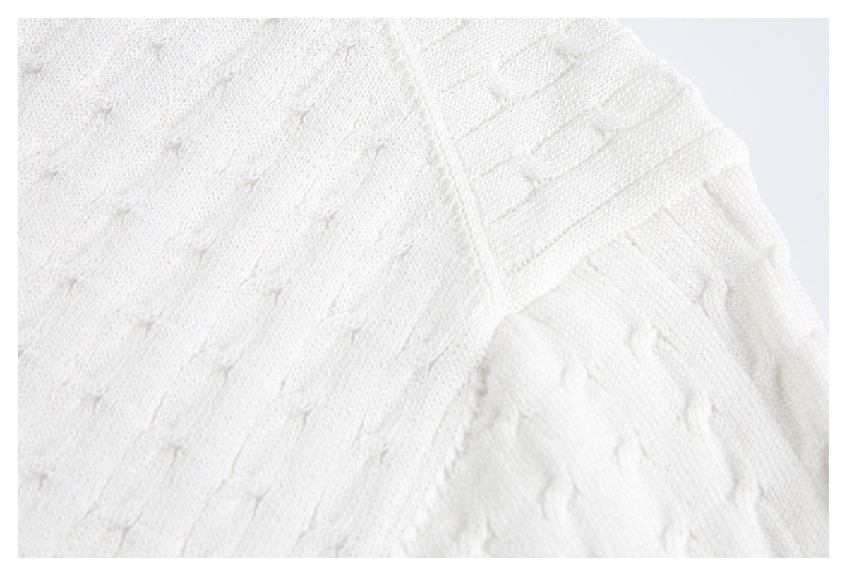 Close-up of white knit fabric with small raised stitches and a ribbed edge.