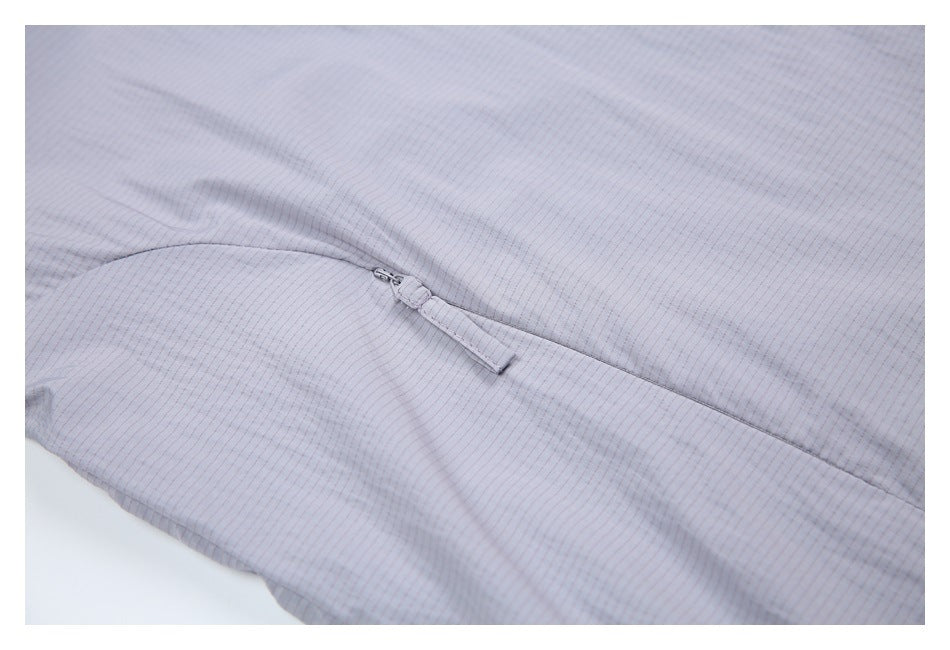 Close-up of a pale gray-lavender jacket sleeve with a small zipper and fabric pull.