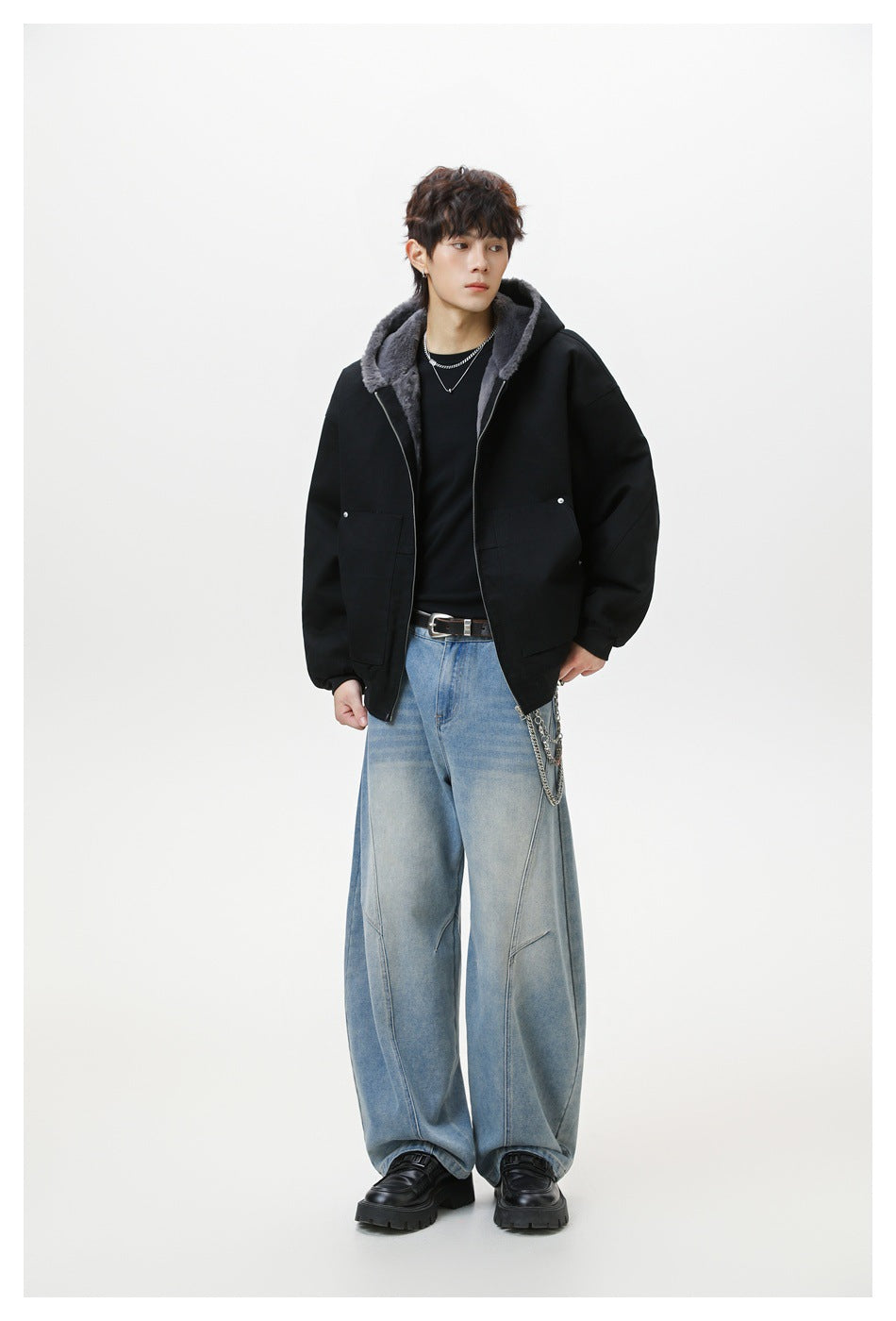 Model wearing an open black hooded jacket with gray fleece-like lining over a black top and wide-leg light-wash jeans