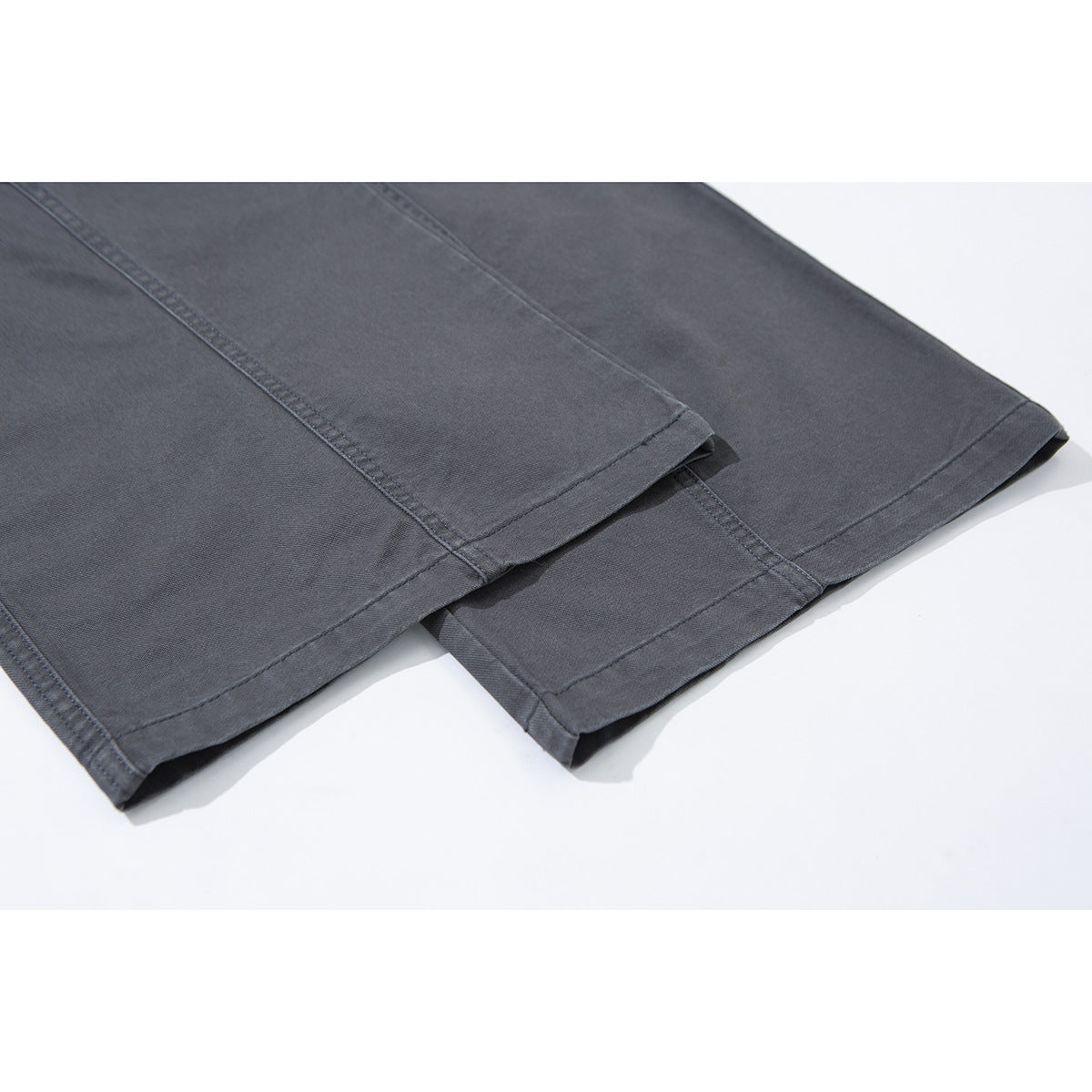 Close-up of charcoal-gray wide-leg trousers showing the stitched hems and leg seams.