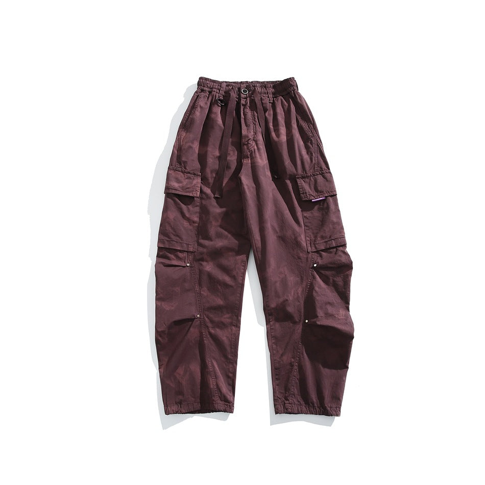 Front view of burgundy cargo pants with an elastic drawstring waist, large side pockets and elastic cuffs.