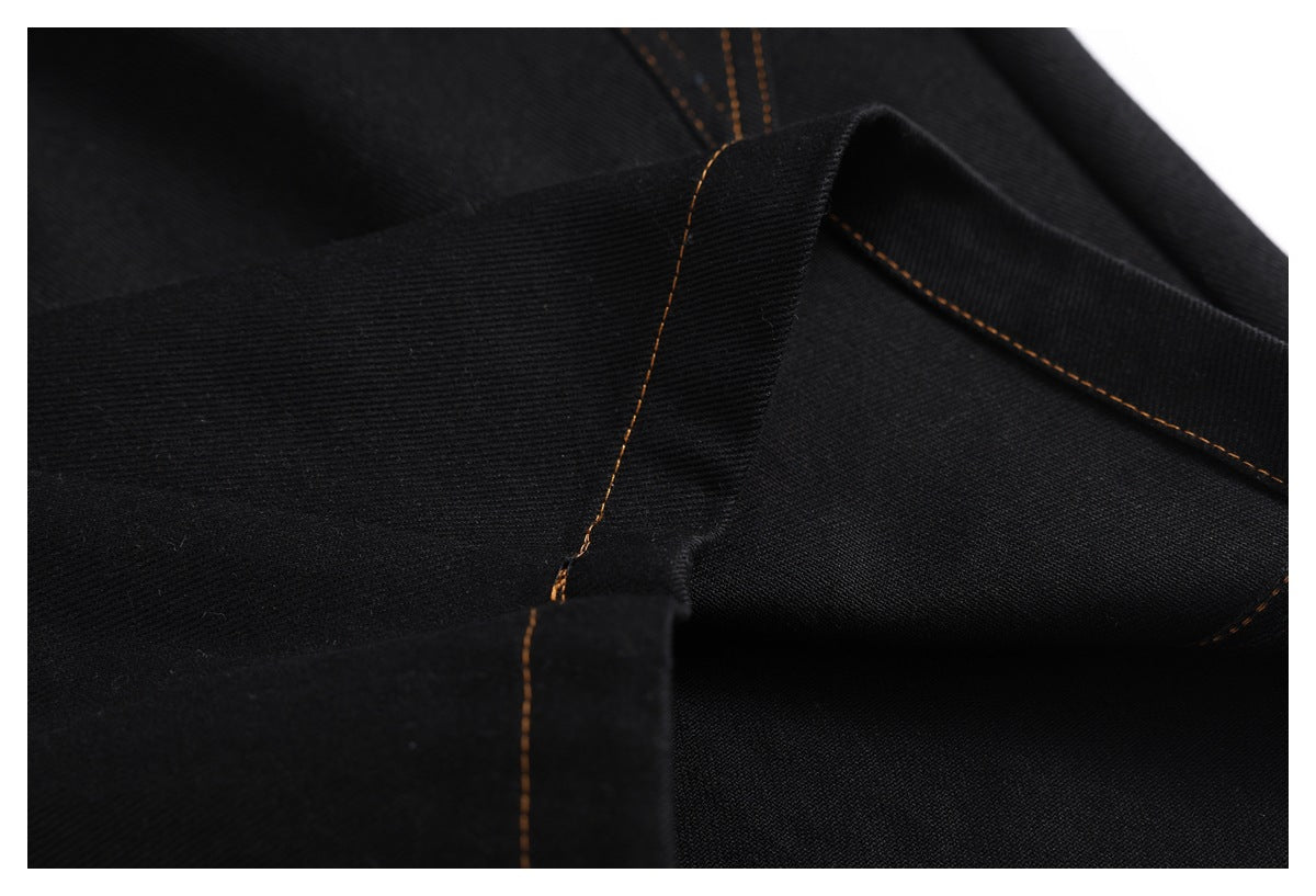 Close-up of black denim waistband construction with a belt loop and brown topstitching.