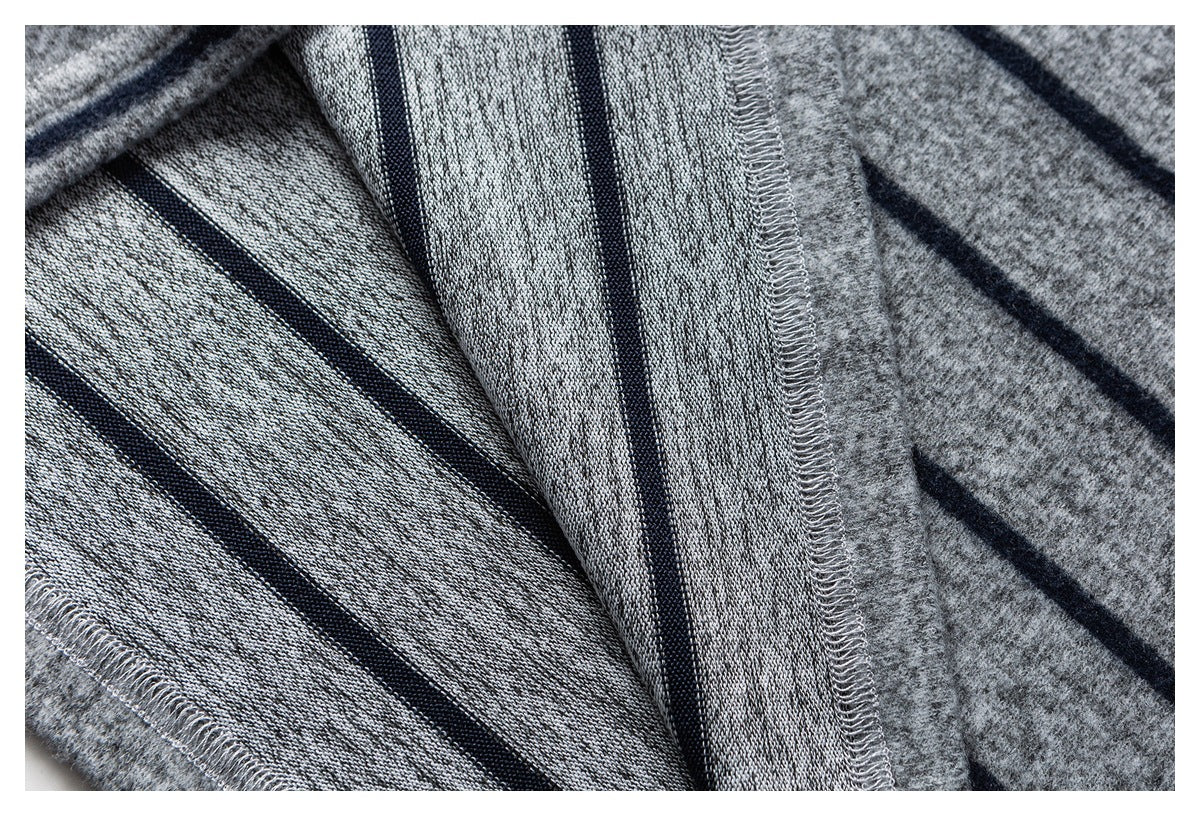 Close-up of gray knit fabric with navy stripes, showing the reverse side and overlocked seams.