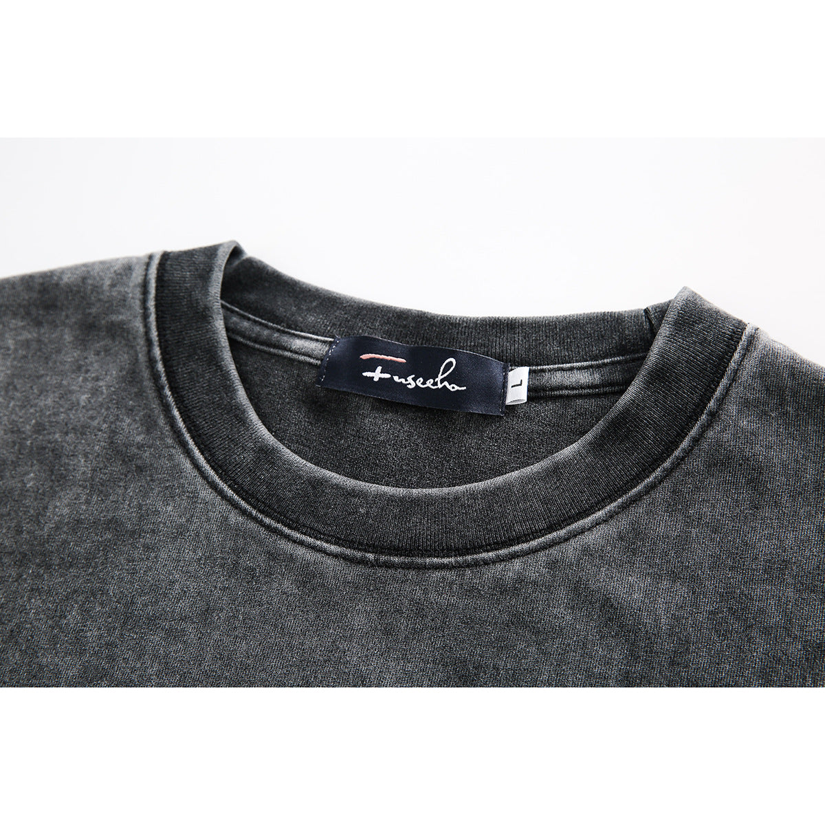 Close-up of a charcoal gray T-shirt neckline with ribbed collar and a sewn-in dark label.