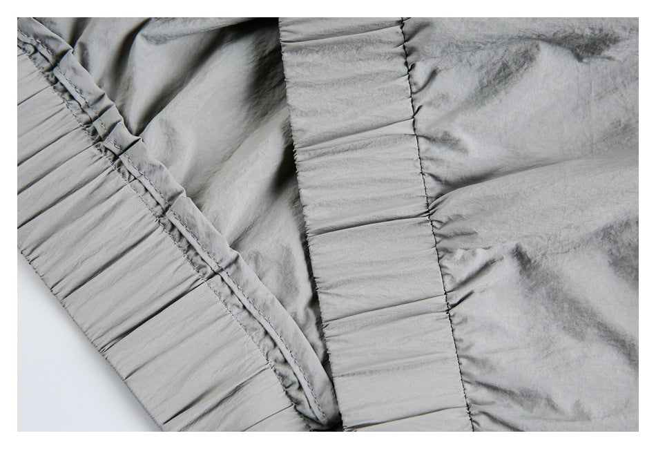 Close-up of gathered elastic trim and stitched construction on the light gray jacket.