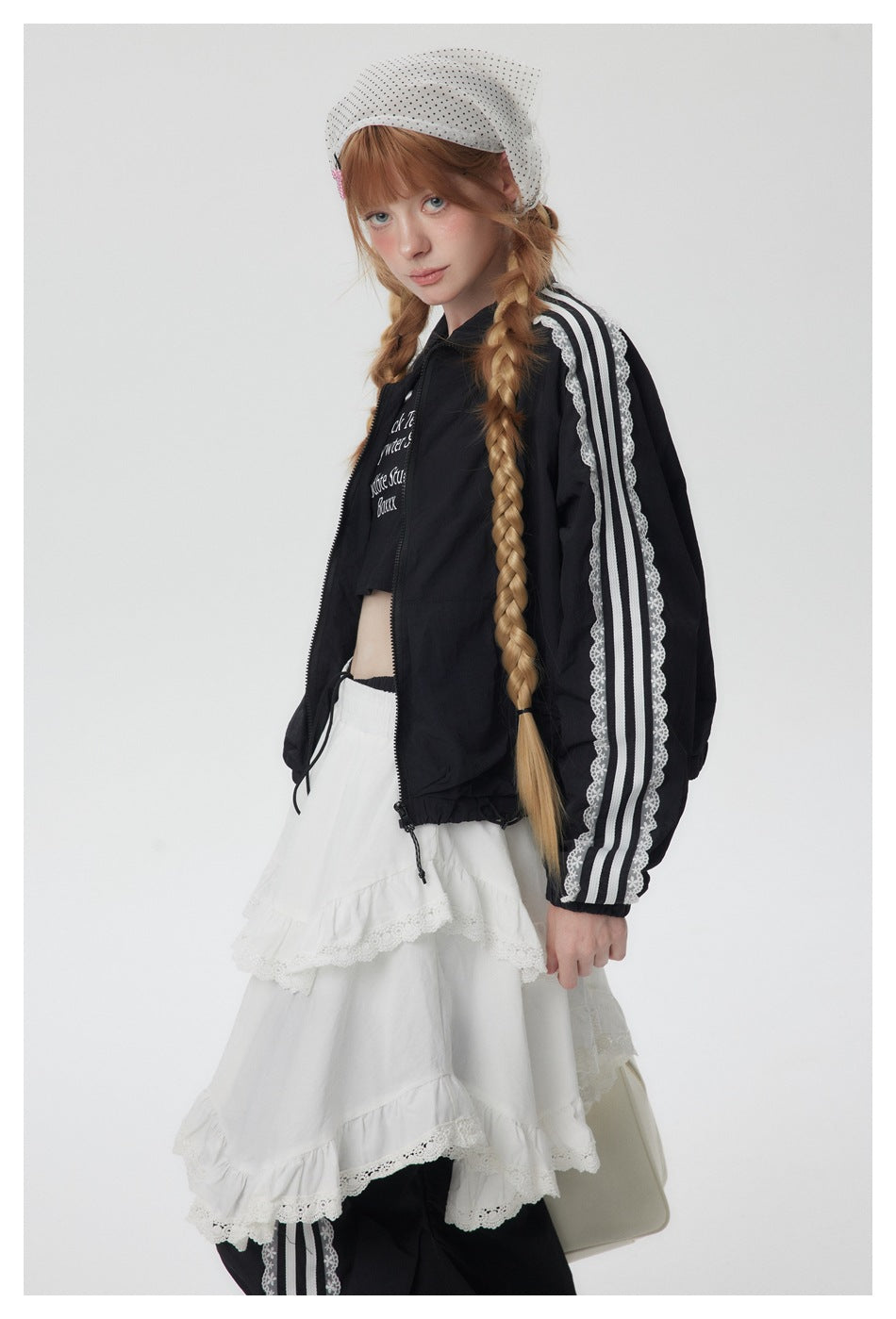 Model wearing a black zip jacket with white striped lace sleeves and a layered white lace-trim skirt.