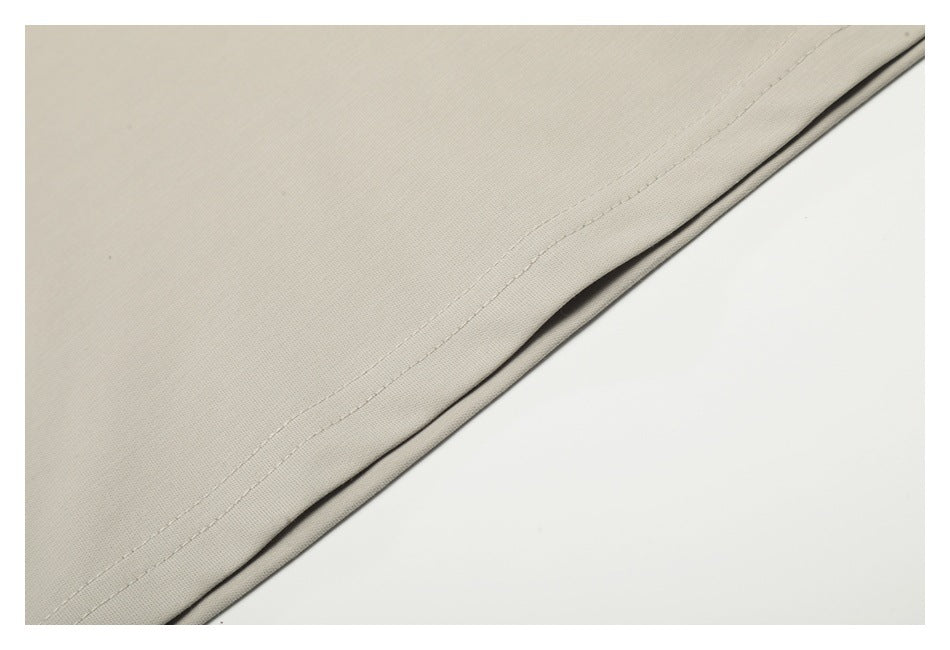 Close-up of a light beige garment hem showing a straight line of stitching.